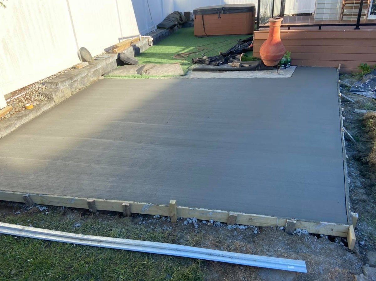 Freshly poured plain concrete slab with a broom finish for an outdoor entertaining area.