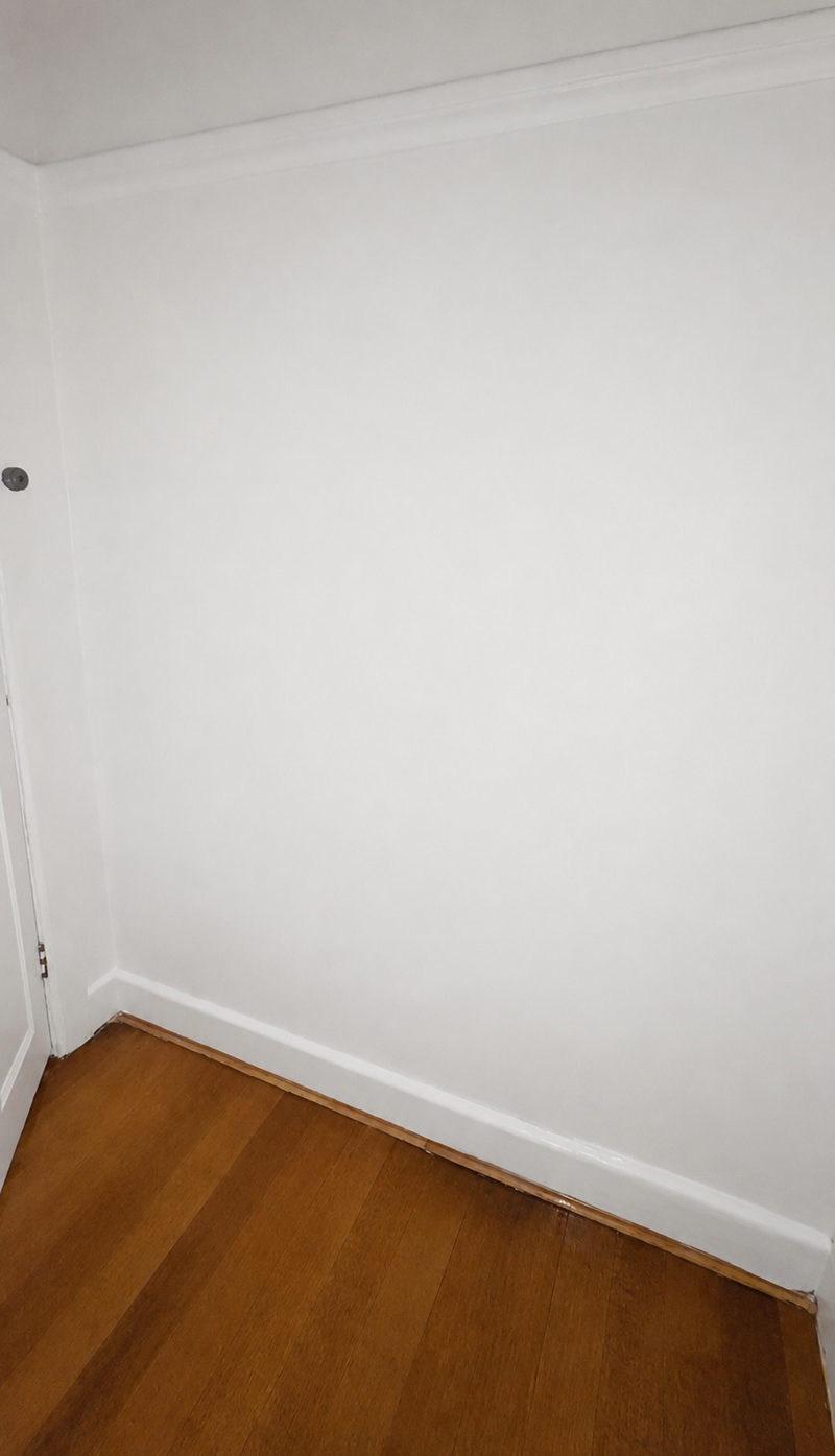 An empty room corner with a plain white wall that was recently plastered and painted.